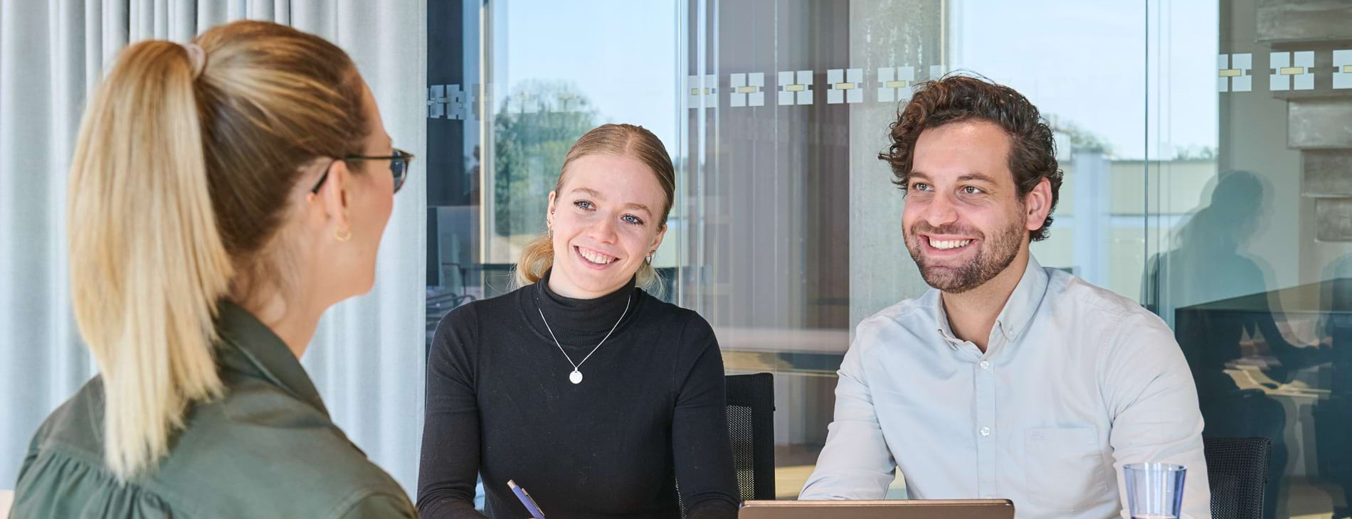 Drei Mitarbeitende in einem modernen B&uuml;ro w&auml;hrend eines Teammeetings; zeigt Zusammenarbeit, HR-Arbeit und kollegiale Unternehmenskultur